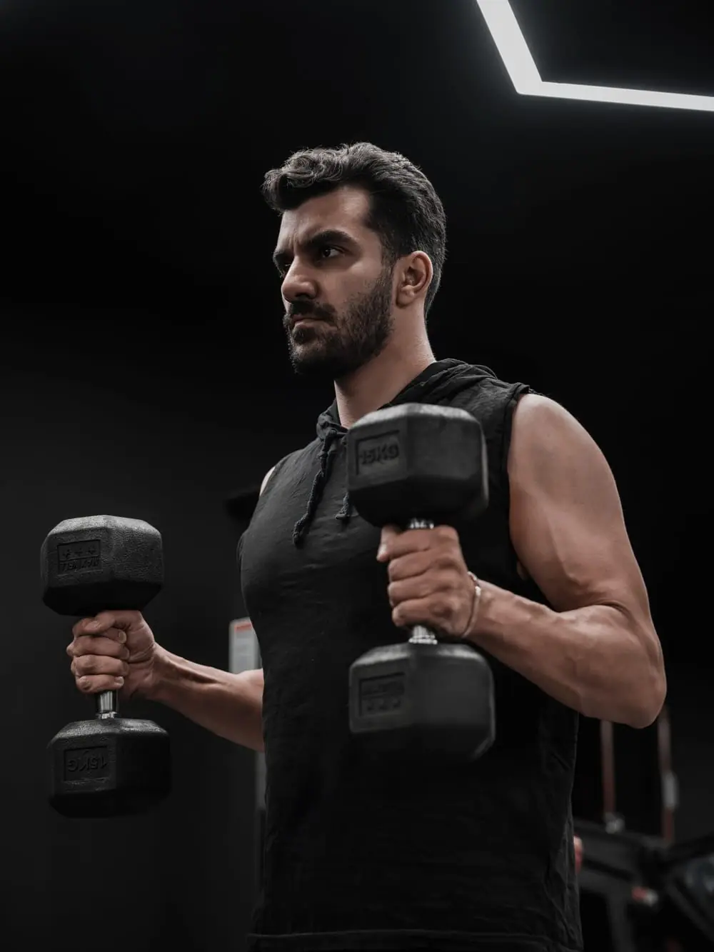 Adam Kowalski in a darkened gym under a single directional light.