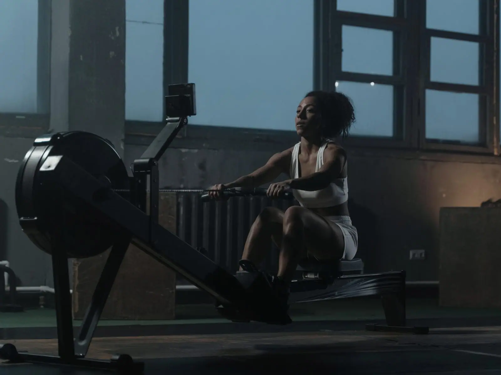 Hard interval work on a rower in a dim room, one cold light from the side.
