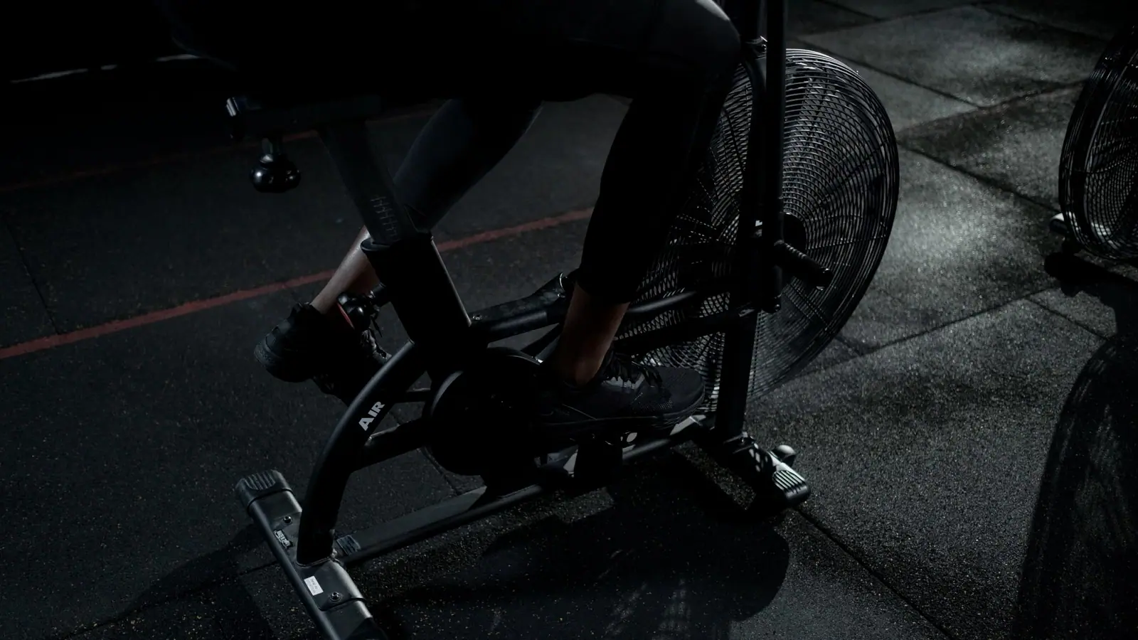 Interval effort on the assault bike, lit low and directional.