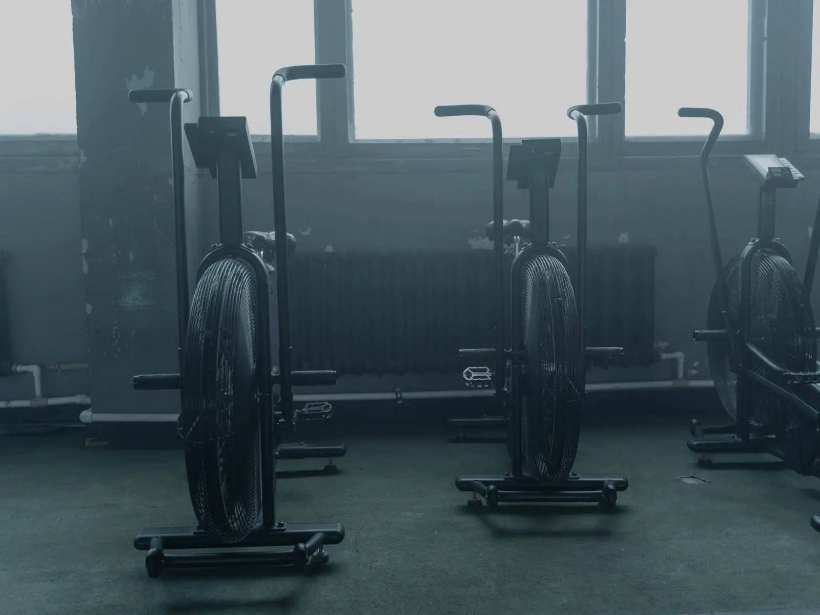 A row of power-metered bikes in a dark, unlit studio.