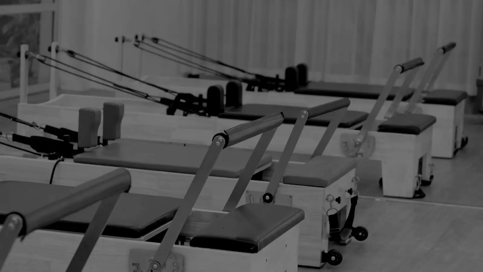 Two rows of empty reformer carriages receding across a darkened studio.