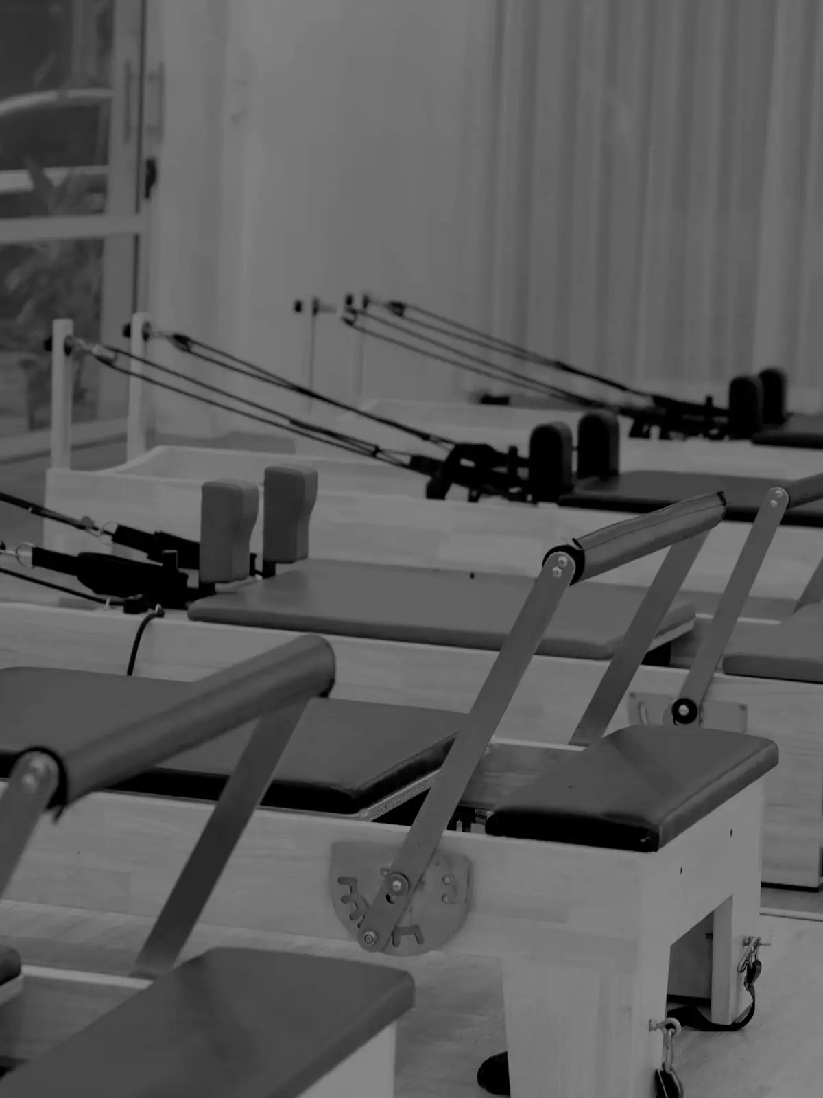 The reformer studio, empty, a row of carriages in low light.