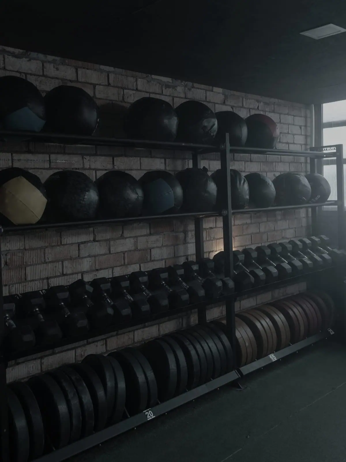 The floor: racked plates and medicine balls against brick, lit low.