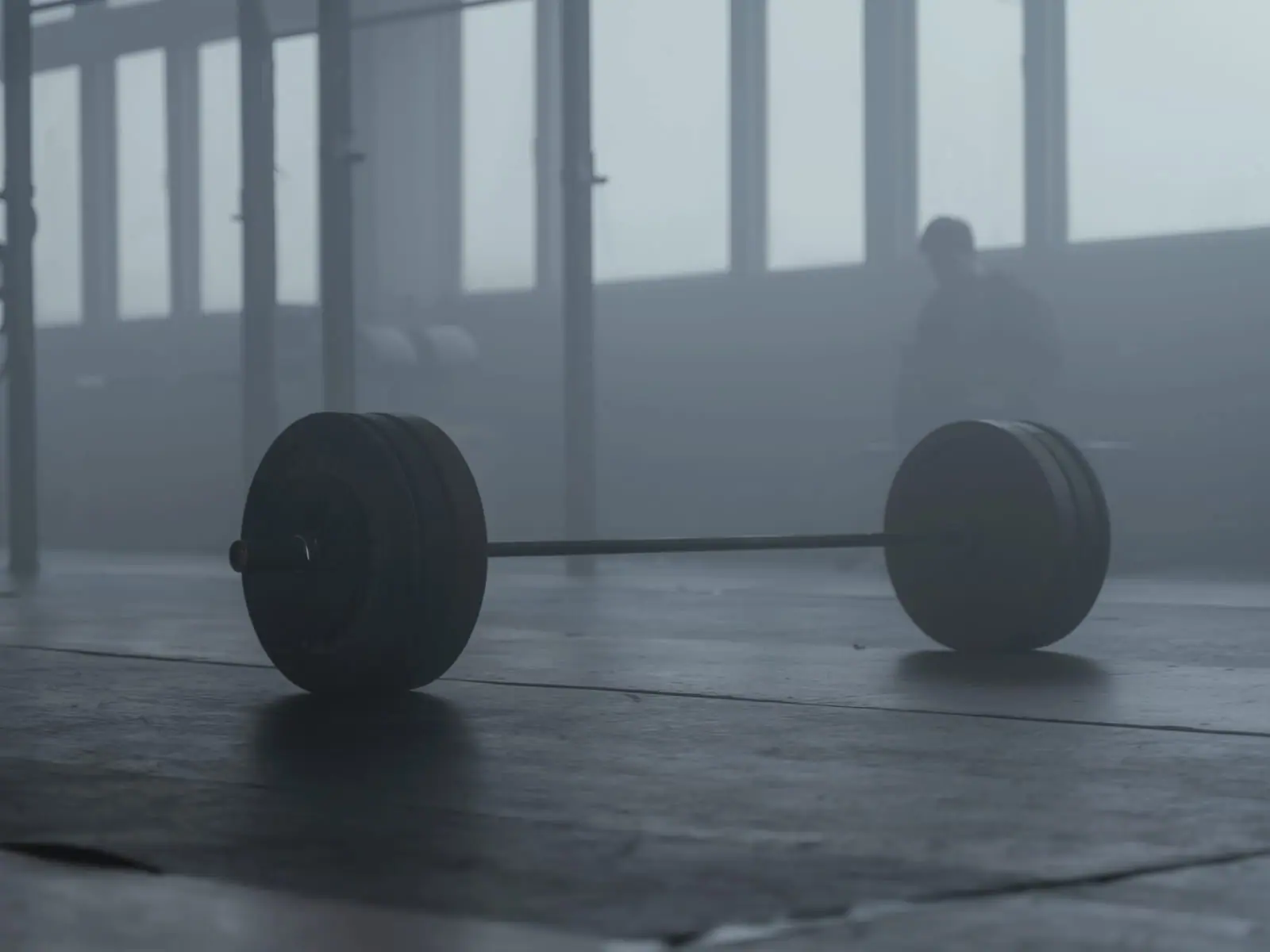 A single loaded barbell on the platform of a dark, low-lit gym.